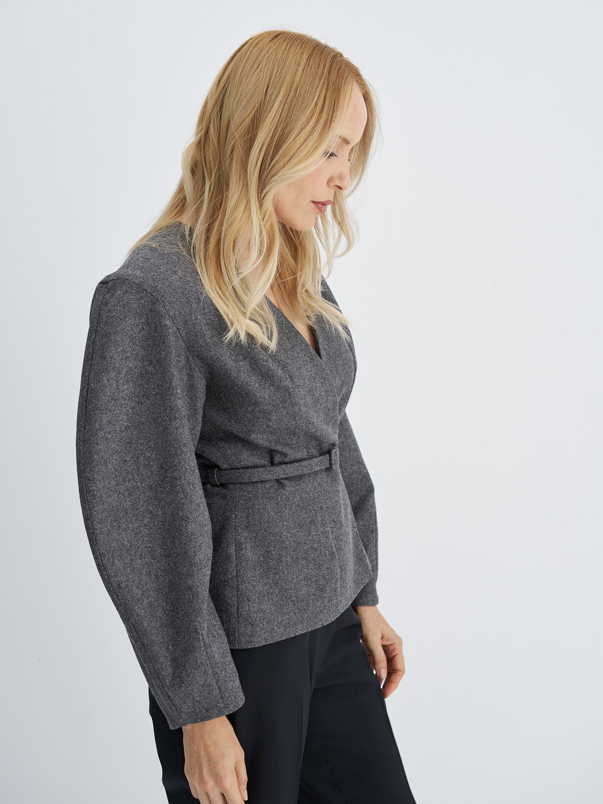 Front view of charcoal grey wool jacket with a V-neckline, sculptural sleeves and a matching narrow belt