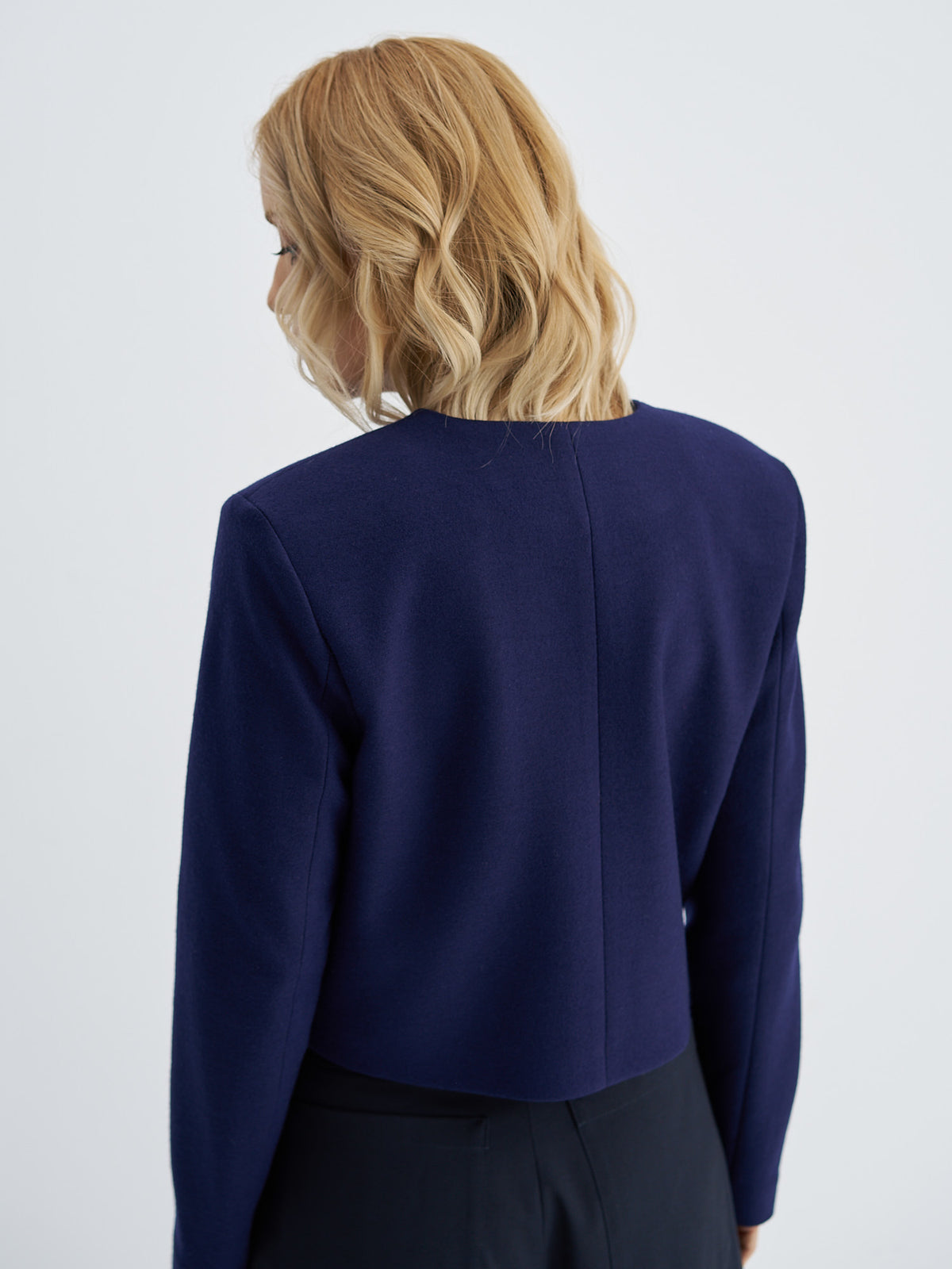 Back view of indigo navy cropped wool jacket showing the centre seam and straight hem