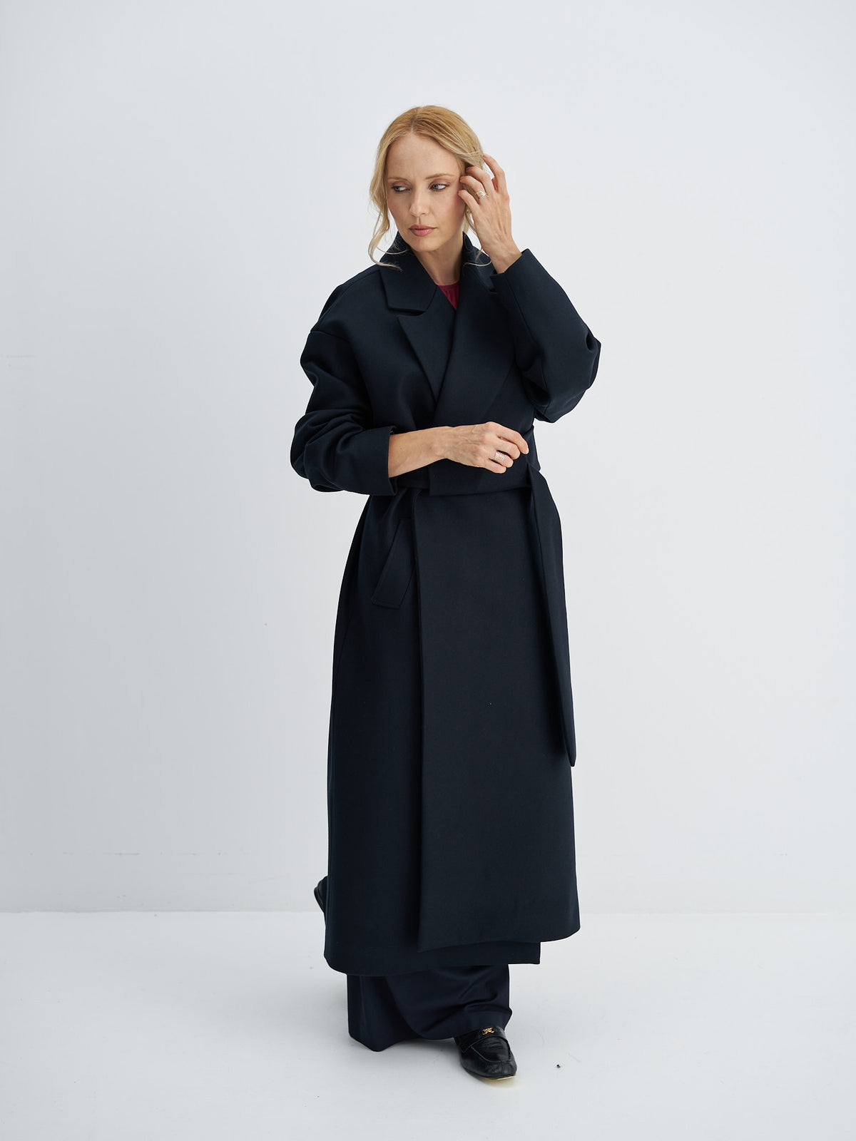Full-length view of the belted wool winter coat worn over wide-leg trousers