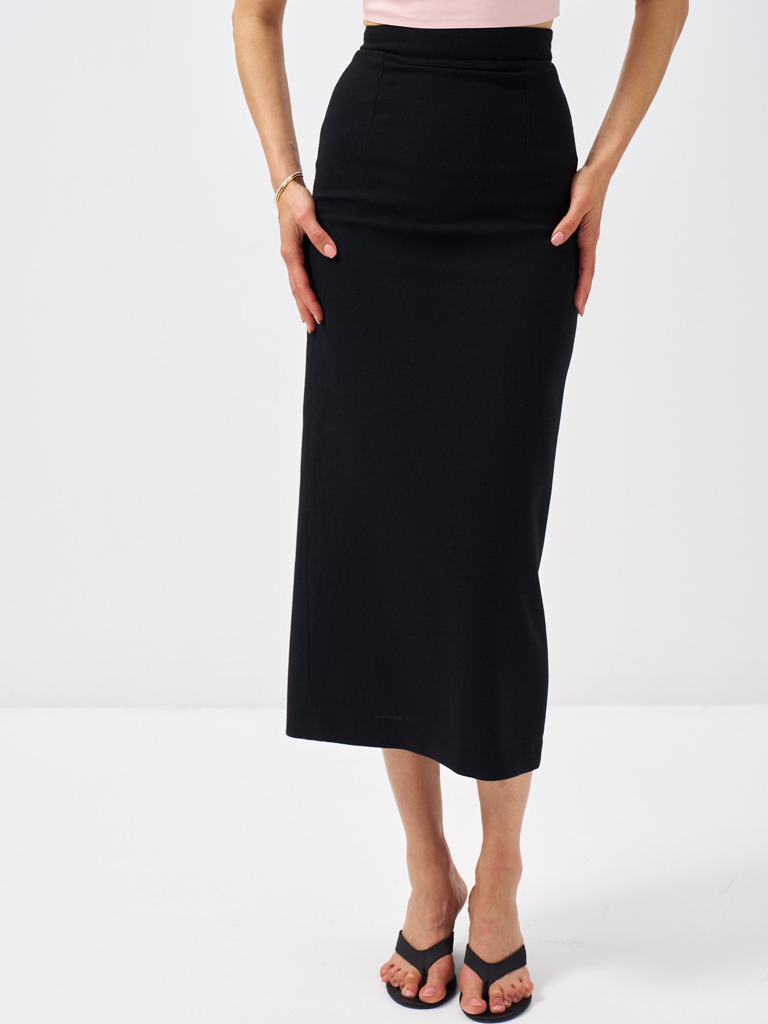 Front view of a tailored black wool midi skirt with a high waist and fitted shape