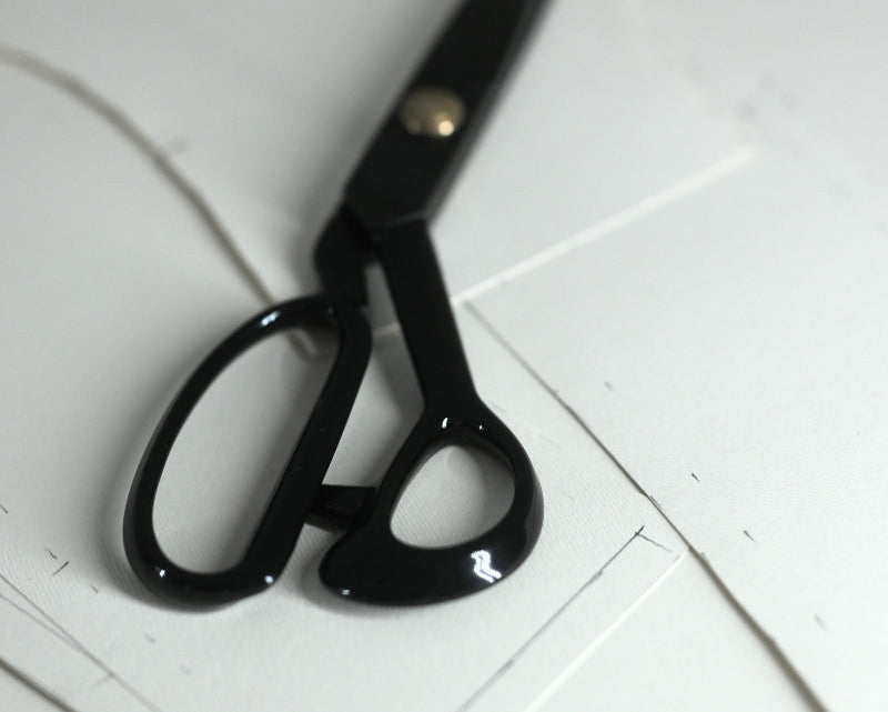 Black scissors on a white tiled floor