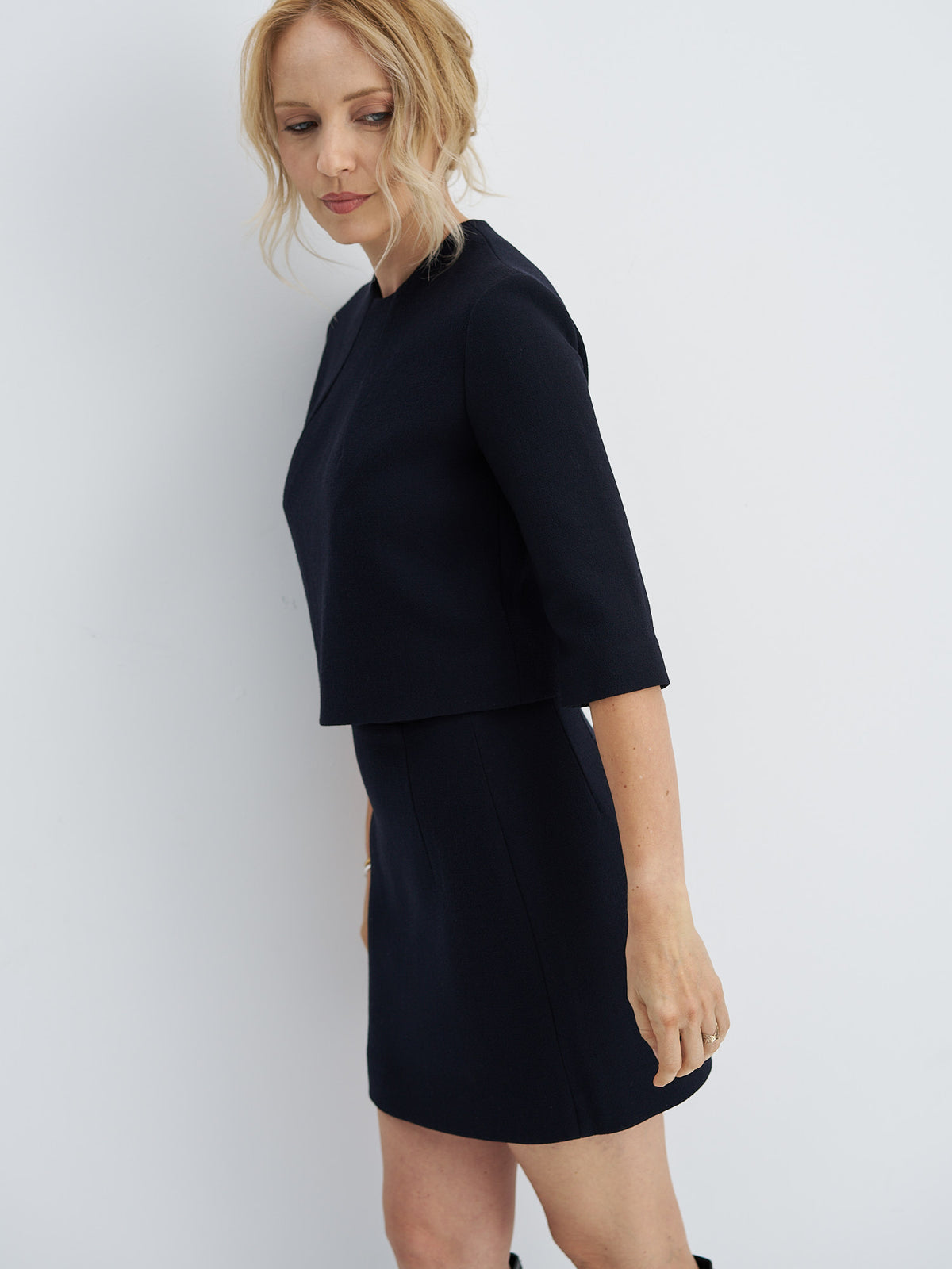 Front view of wool-crepe crop top with a round neckline and curved seams, worn with a coordinating mini skirt