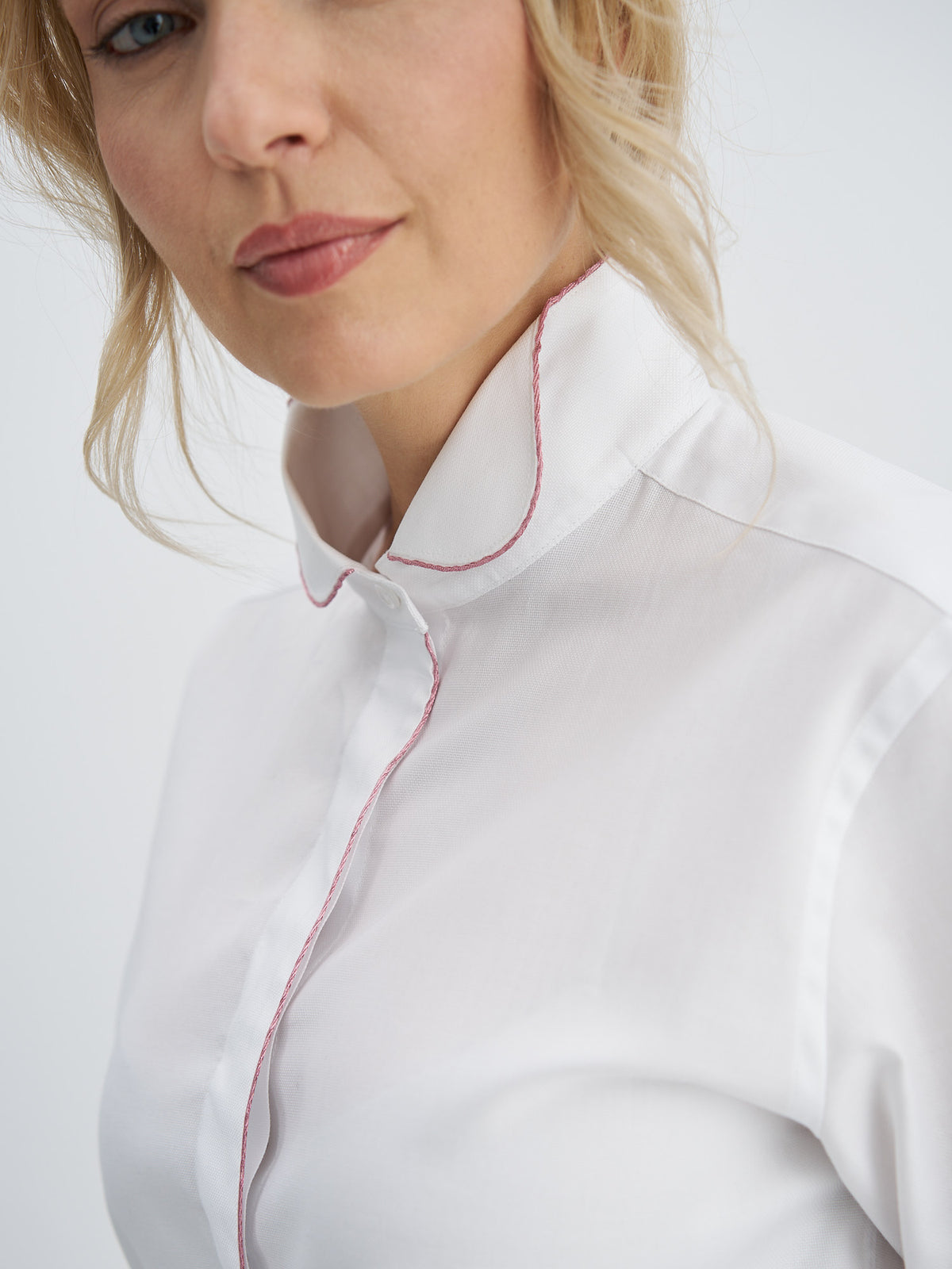 Angled close-up of the wing collar, pink metallic-thread piping and mother-of-pearl top button