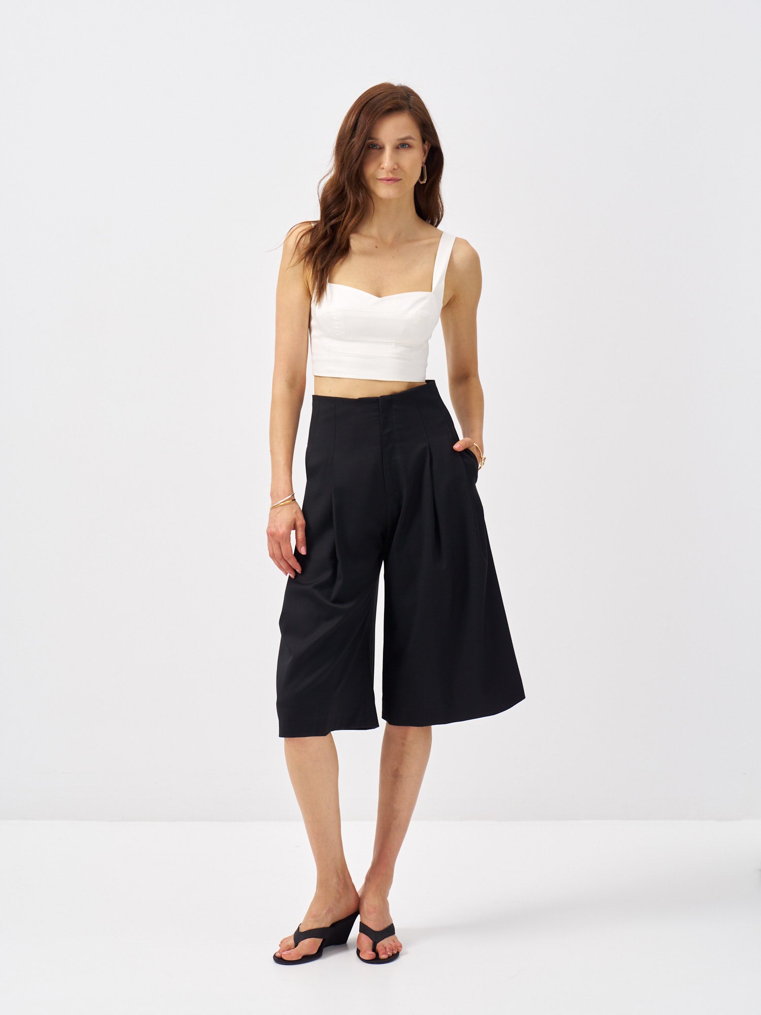 Front view of black Super 120's wool bermuda shorts with a high-rise waist and front pleats