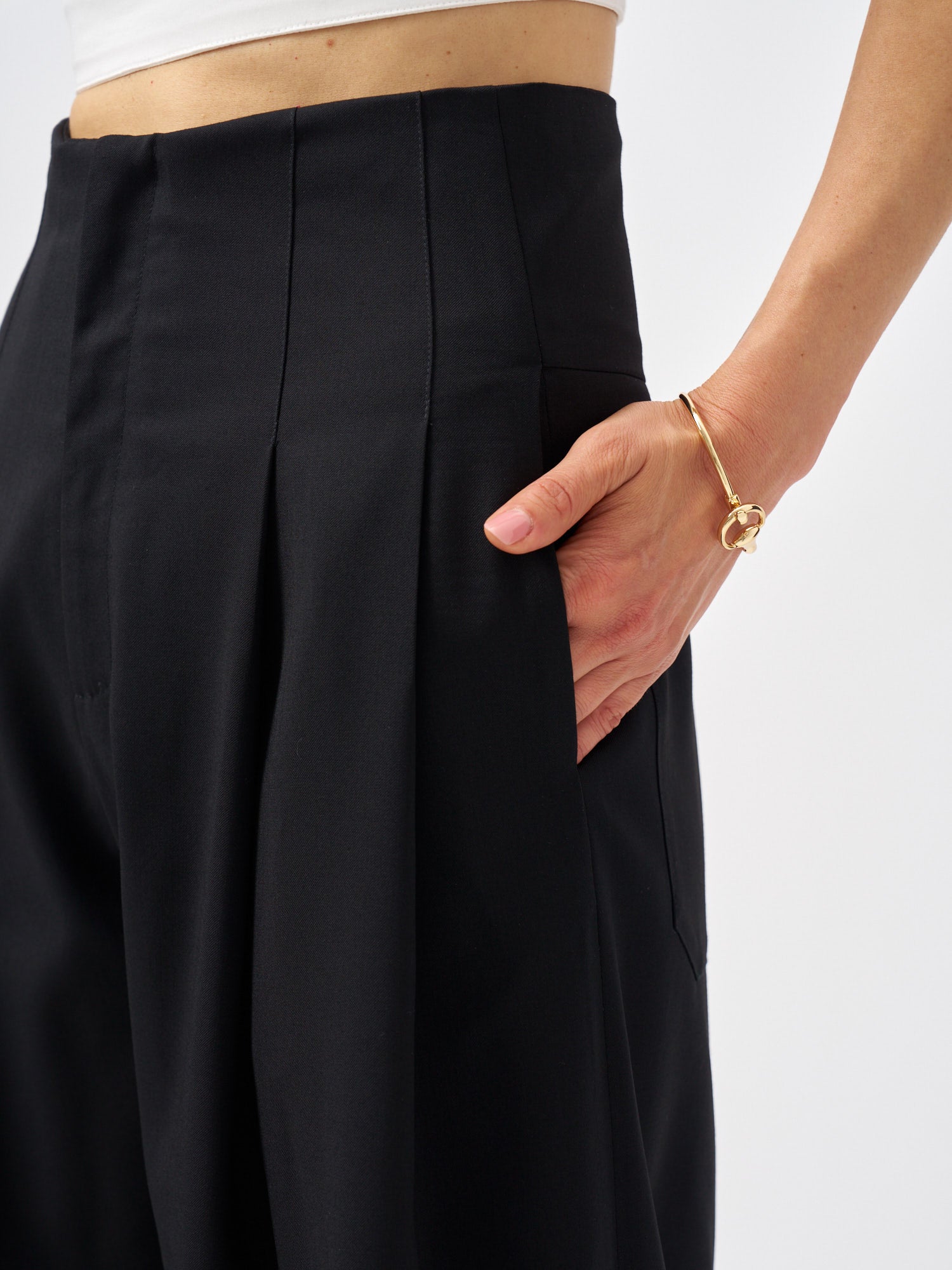 Side view of tailored black wool bermuda shorts featuring a fluid wide-leg silhouette