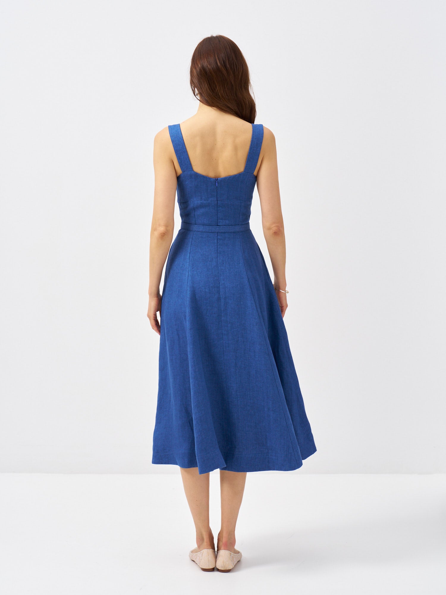 Back view of a blue belted linen midi dress with wide straps, fitted waist and full flowing skirt.