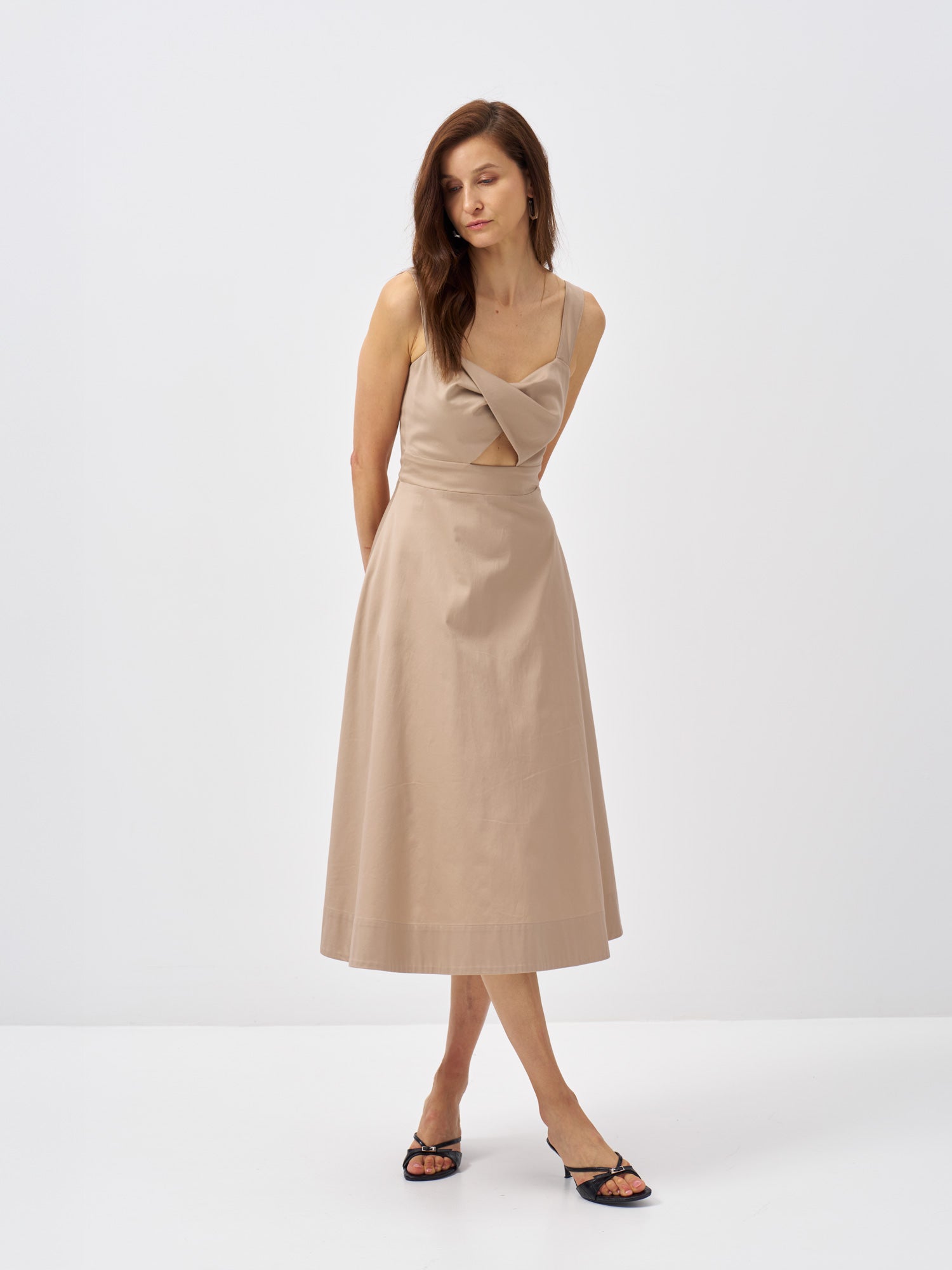 Front view of a beige midi dress featuring a crossover neckline and softly flared skirt.