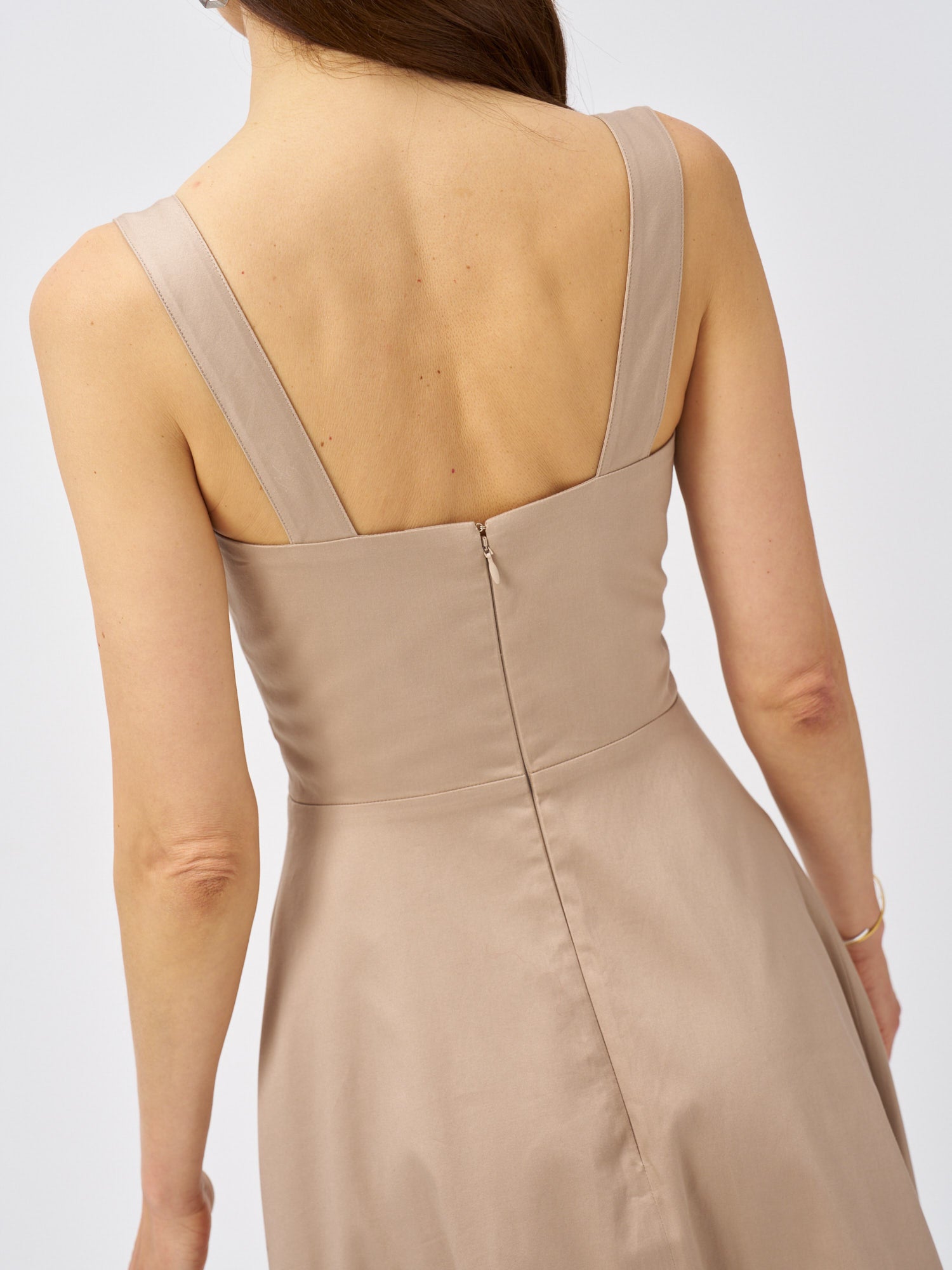Back detail of a beige midi dress with wide straps and concealed zip fastening.